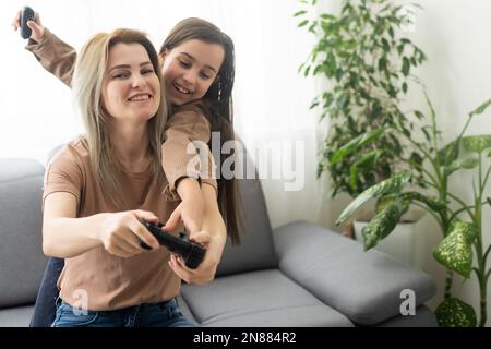 Mère et fille jouant à des jeux vidéo sur ordinateur portable à la maison. Banque D'Images