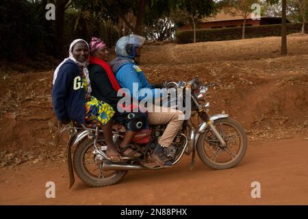 Caratu, Tanzanie - 16 octobre 2022: Trois personnes qui font une moto sur une route de terre en Tanzanie. Banque D'Images