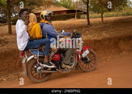 Caratu, Tanzanie - 16 octobre 2022: Trois personnes qui font une moto sur une route de terre en Tanzanie. Banque D'Images