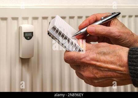 Les mains de l'homme enregistrent les relevés de consommation de chaleur sur un radiateur de chauffage. Gros plan. Banque D'Images
