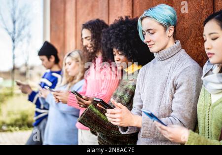 Groupe de personnes diverses utilisant un smartphone sur le campus universitaire - jeunes amis addictés partageant du contenu sur un smartphone mobile - Tech Life style co Banque D'Images