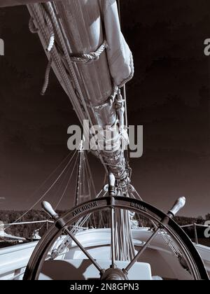 Photographie sépia d'un détail de grand navire vintage montrant une roue antique et une grande voile à fourrure Banque D'Images