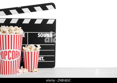 Tasses avec délicieux pop-corn et papperboard sur table en bois sur fond blanc Banque D'Images