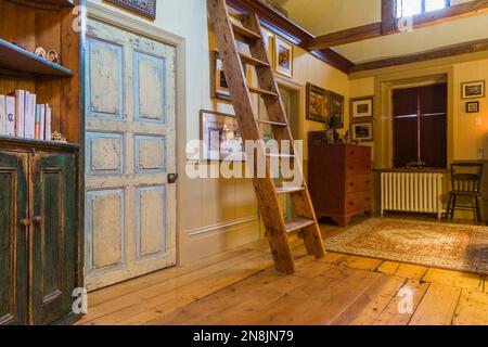 Couloir avec de larges planches de bois de pin, bibliothèque, escaliers de Miller et portes de chambre en détresse à l'étage à l'intérieur de la vieille maison circa 1805. Banque D'Images