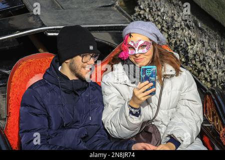 Venise, Italie. 11th févr. 2023. Un couple apprécie leur promenade en gondole en regardant les procédures du carnaval. Les participants au carnaval costumés se mêlent avec les touristes, les visiteurs et les habitants tandis que le week-end du carnaval commence à se balancer dans les rues et les places de Venise. Credit: Imagetraceur/Alamy Live News Banque D'Images