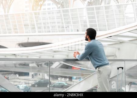 Voyageur masculin méconnaissable du Moyen-Orient debout avec Suitcase à l'aéroport Banque D'Images