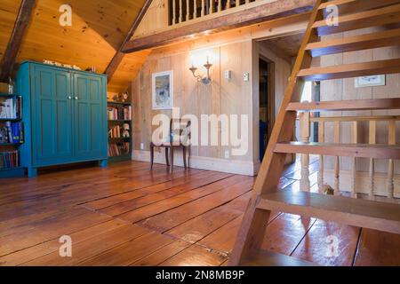 Armoire en bois antique peinte en bleu sarcelle, bibliothèque, chaise rembourrée rouge et escalier de Pinewood Miller dans la salle de lecture à l'étage à l'intérieur de la vieille maison de 1760. Banque D'Images