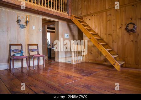 Fauteuils anciens en bois tapissés rouges et escaliers de Pinewood Miller dans la salle de lecture à l'étage à l'intérieur de la vieille maison de circa 1760. Banque D'Images