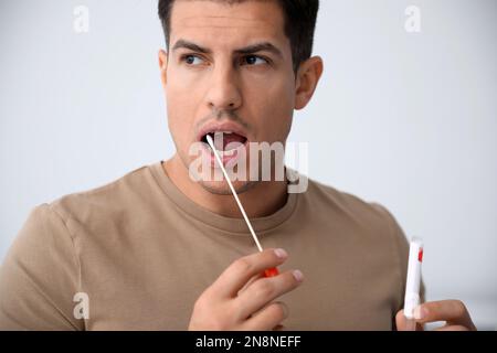 Homme prenant l'échantillon pour le test d'ADN sur fond clair Banque D'Images