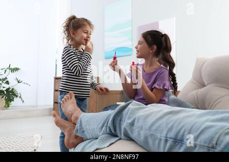 Petits enfants mignons appliquant du vernis sur les ongles du père pendant qu'il dormait à la maison, en gros plan Banque D'Images