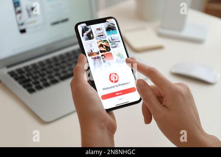 MYKOLAIV, UKRAINE - 28 AOÛT 2020: Femme tenant l'iPhone 11 avec l'application Pinterest à l'écran à la table, gros plan Banque D'Images