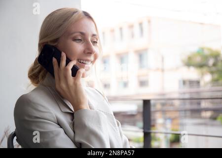 Belle jeune femme d'affaires caucasienne assis et parlant sur un smartphone avec se détendre au bureau, femme d'affaires se détendre en parlant sur un smartphone avec Banque D'Images