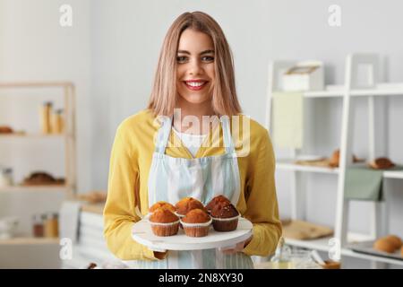 Boulanger femme avec plateau de délicieux petits gâteaux dans la cuisine Banque D'Images