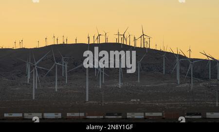 Des éoliennes et un train de marchandises passant sont présentés au crépuscule près de la ville de Mojave dans le comté de Kern, Californie, États-Unis. Banque D'Images