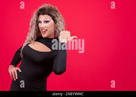 Personne transgenre souriant à l'appareil photo et pointant vers le côté Banque D'Images