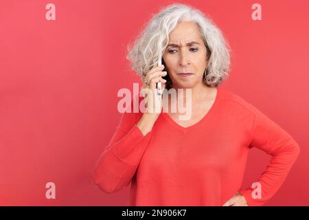 Une femme mûre en colère parlant sur le téléphone portable Banque D'Images