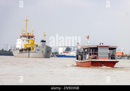 SAMUT PRAKAN, THAÏLANDE, NOVEMBRE 13 2022, le ferry transporte des passagers sur la rivière Chao Phraya, sur un fond ancré trémie aspirante traînante Banque D'Images