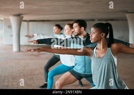 Réveillez votre guerrier intérieur. un groupe d'amis pratiquant la posture du yoga guerrier. Banque D'Images