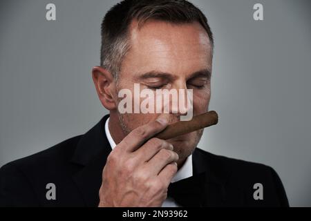 Richesse, vintage et visage de l'homme avec des cigares pour fumer habit sur fond gris pour le luxe, la puissance et le succès. Retraite, gangster d'affaires et Banque D'Images