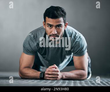 Pensez que vous pouvez le tenir plus longtemps que moi. Portrait complet d'un jeune athlète masculin en position de pont sur fond gris. Banque D'Images