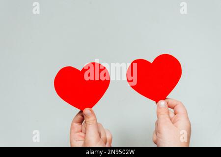 Dans les mains des enfants, un coeur rouge fait de papier Saint-Valentin Banque D'Images