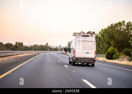 Mini-fourgonnette industrielle commerciale compacte, blanche et légère avec échelle sur le toit pour transporter des marchandises à l'intérieur de la route jusqu'au point de service Banque D'Images