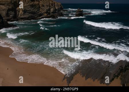 Les vagues de l'Atlantique s'alignent pour se briser dans une crique de sable sur les côtes accidentées de Cabo Carvoeiro à Peniche dans le district de Leiria, au centre du Portugal. Le littoral est incroyablement beau, mais ses rochers éparpillés ou ses piliers de mer et ses obstacles sous-marins ont provoqué la naufrage de nombreux navires et la perte de la vie des gens de mer. Banque D'Images