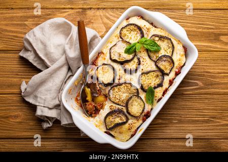 Moussaka, cuisine grecque méditerranéenne, aubergines cuites au four, bœuf haché dans une casserole en céramique blanche avec serviette en bois sur fond rustique Banque D'Images