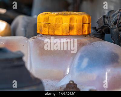 Réservoir en plastique avec un bouchon jaune pour l'antigel du circuit de refroidissement du moteur de voiture. Réservoir en plastique avec couvercle jaune. Contenant de liquide. Ravitaillement en antigel. Banque D'Images