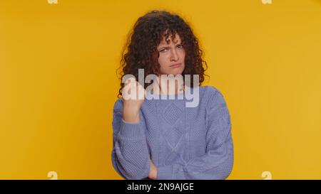 Une femme agressive et furieuse en colère tente de se battre à la caméra, en branlant le poing, en boxe avec expression, en châtiment, en déception, rage, querelle. Jeune fille adolescente isolée sur fond jaune studio Banque D'Images