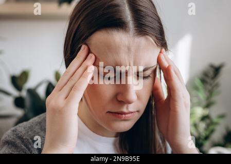 Gros plan portrait de la jeune fille déprimée frustrée sentir l'anxiété de stress, inquiet fatigué bouleversé dame souffrent de sentir mal de tête. Triste brunette W Banque D'Images