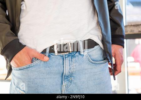 Homme portant une veste et un Jean avec une élégante ceinture en cuir noir. Gros plan de l'accessoire d'artisanat. Mode et style moderne décontracté. Banque D'Images