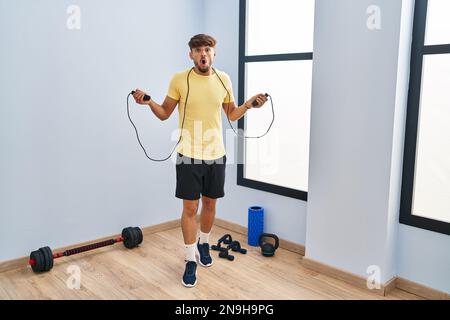 Homme arabe avec formation de barbe avec corde de saut peur et choqué avec la surprise et l'expression stupéfaite, la peur et le visage excité. Banque D'Images
