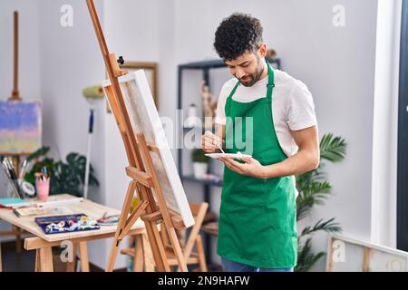 Jeune artiste homme arabe souriant et confiant, dessin au studio d'art Banque D'Images