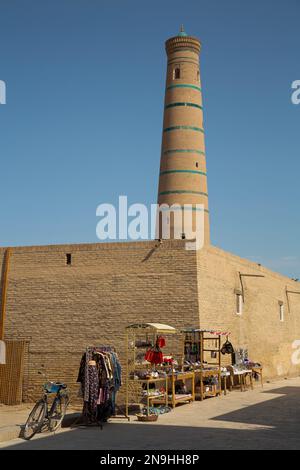 Produits touristiques à vendre (premier plan), Juma Minaret (arrière-plan), Ichon Qala, Khiva, Ouzbékistan Banque D'Images