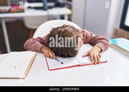 Adorable étudiante hispanique de fille a souligné se pencher sur le livre en classe Banque D'Images