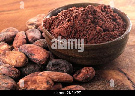 Fèves de cacao et tas de poudre de cacao sur fond de bois Banque D'Images