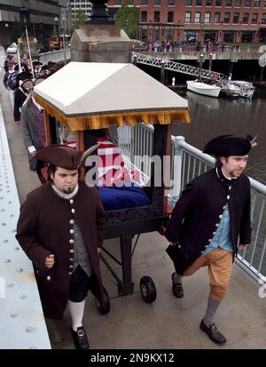 Colonial reenactors pull a carriage carrying one of the original tea chests from the 1773 Boston Tea Party, draped in the American flag, during a procession to the Boston Tea Party Ships and Museum, in Boston, Wednesday, June 13, 2012. The Robinson Half Tea Chest, which was recovered from sand off Boston Harbor the morning after colonists tossed 340 tea chests into the water in an act of rebellion, is believed to be one of two remaining. The chest will make its way from the Old South Meeting House to the Boston Tea Party Ships and Museum, which is slated to open June 26. (AP Photo/Steven Senne