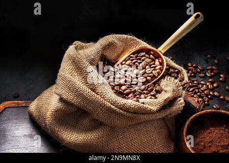 Une cuillère de grains de café dans un sac sur planche noire. Café moulu dans une tasse et café instantané dans une tasse en bois. Placer pour le texte. Banque D'Images