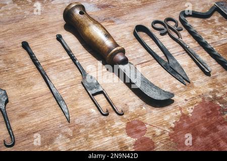 Une sélection d'instruments chirurgicaux médiévaux sur une table en bois en lambeaux de sang Banque D'Images