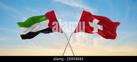 Deux drapeaux croisés la suisse et les Émirats arabes Unis agitant dans le vent à ciel nuageux. Concept de relation, de dialogue, de voyage entre deux pays Banque D'Images