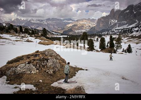 Les skieurs négocient des rochers sur les pistes de ski de Passo Di Sella dans les Dolomites où le manteau neigeux fond et diminue chaque année en raison du tempérament chaud... Banque D'Images