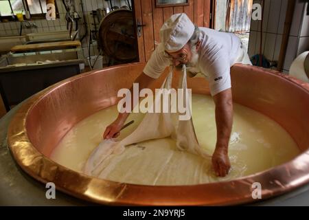 Le travailleur étale le tissu de fromage tout en faisant du fromage Alkase dans une bouilloire en cuivre. Une caractéristique caractéristique des fromages suisses est l'utilisation du cuivre. Dans... Banque D'Images