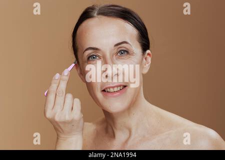 Portrait d'une femme moderne souriante avec des pinces isolées sur fond beige. Banque D'Images