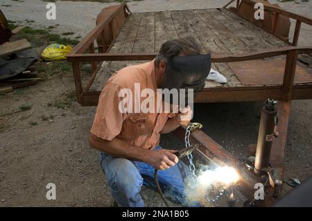 Hommes soudant à l'extérieur sur une ferme ; Nebraska, États-Unis d'Amérique Banque D'Images