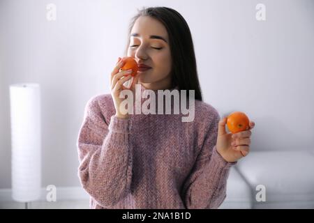 Bonne jeune femme avec des mandarines fraîches et mûres à la maison Banque D'Images