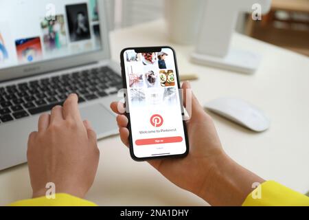 MYKOLAIV, UKRAINE - 28 AOÛT 2020: Femme tenant l'iPhone 11 avec l'application Pinterest à l'écran à la table, gros plan Banque D'Images