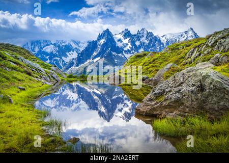 L'aiguille des Charmoz, qui fait partie des aiguilles de Chamonix, se reflète sur le lac Flegere entouré de prairie verte, aiguilles rouges Banque D'Images