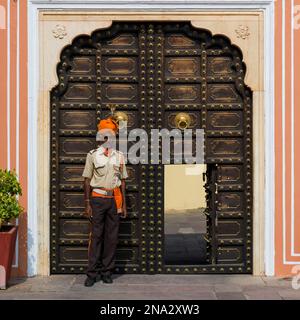 Homme debout à l'extérieur d'une porte ornée au Palais de la ville; Jaipur,Rajasthan, Inde Banque D'Images