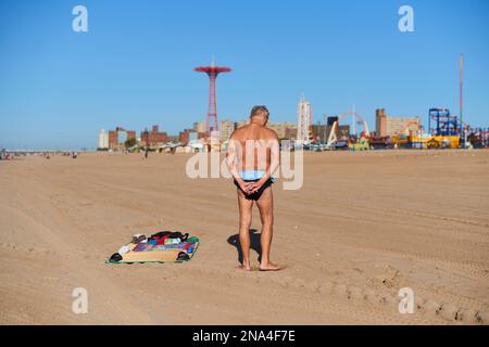 Homme en maillot de bain s'étendant sur la plage de Coney Island; New York City, New York, États-Unis d'Amérique Banque D'Images